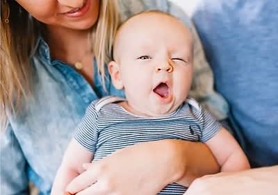 Gähnendes Baby auf dem Schoss einer Frau