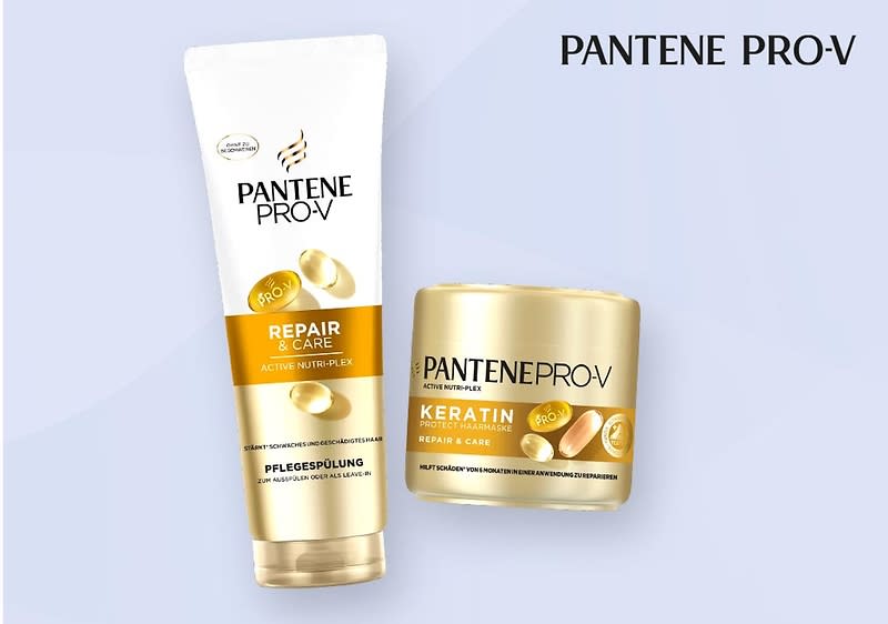 Eine goldene Tube und ein goldener Tiegel der Marke Pantene Pro-V mit der Aufschrift Repair & Care und Keratin sind nebeneinander auf einem hellblauen Hintergrund platziert, die Tube ist mit einem weißen Deckel versehen und der Tiegel hat einen goldenen Deckel, beide Produkte sind mit goldenen und weißen Details gestaltet und die Schrift ist in Schwarz gehalten, oben rechts steht der Markenname Pantene Pro-V in schwarzer Schrift.