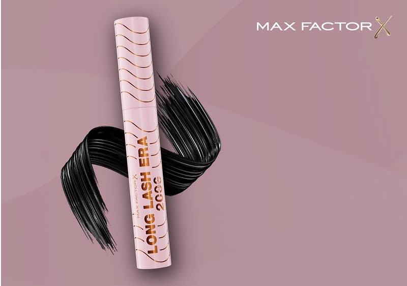 Eine rosa Mascara-Verpackung mit goldener Aufschrift LONG LASH ERA 2000 und einem geschwungenen schwarzen Pinselstrich auf einem dunkelroten Hintergrund, oben rechts steht in weißer Schrift MAX FACTOR X