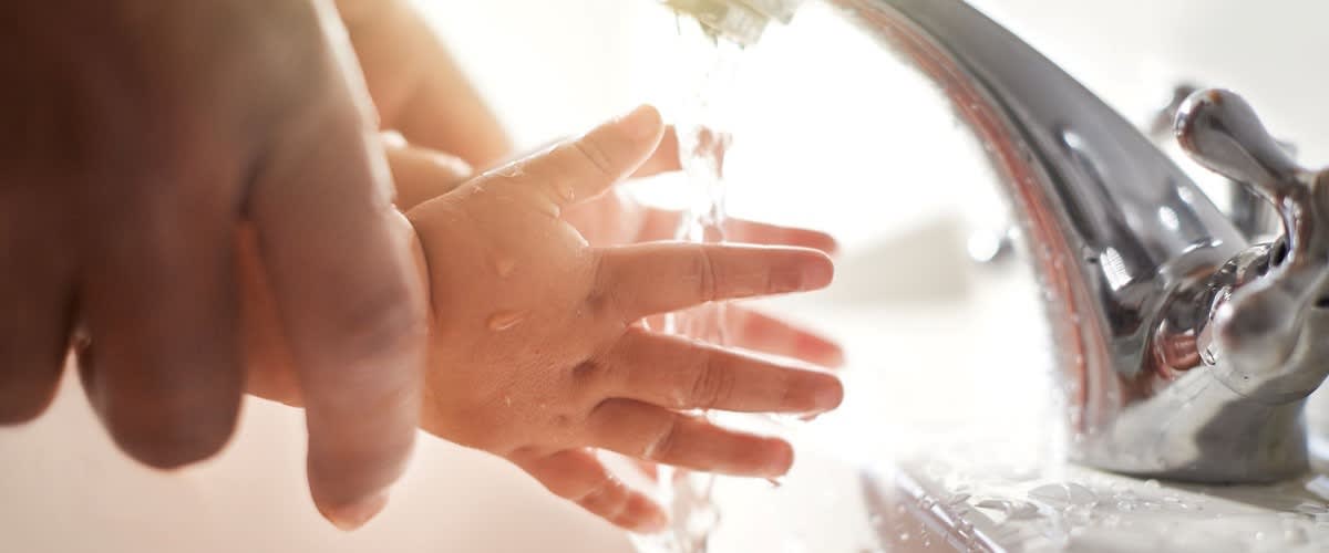 Hände werden unter Wasserhahn gehalten um Brandwunden zu kühlen