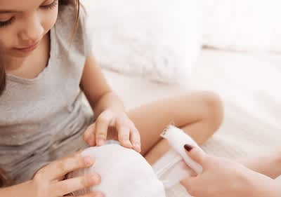 Eine Person hält einen Verband, während eine andere Person einen weiteren Verband anreicht