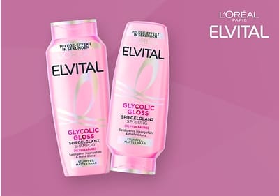 Zwei rosa Flaschen der Marke L'Oréal Paris Elvital sind abgebildet, eine Shampoo- und eine Spülungsflasche mit der Aufschrift Perfekt gepflegt in Sekunden, Glycolic Gloss Spiegelglanz, Shampoo und Spülung sowie Für glanzloses, mattes Haar und Seidenglanz-Pflegeformel in weißer und pinker Schrift auf der Vorderseite, die Flaschen sind leicht schräg nebeneinander positioniert auf einem rosa Hintergrund mit dem Markenlogo oben rechts.