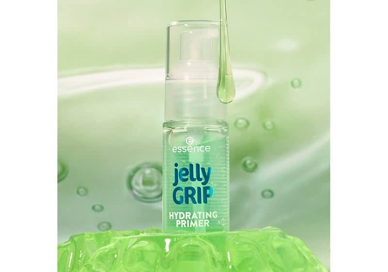 Eine transparente Flasche mit einem Pumpspender, die die Aufschrift essence jelly GRIP HYDRATING PRIMER trägt, steht auf einer grünen, geleeartigen Oberfläche, während ein Tropfen einer klaren Flüssigkeit von oben herabfällt.