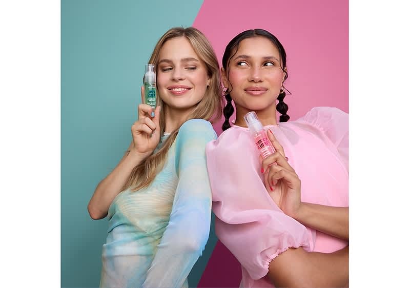 Zwei Personen stehen nebeneinander vor einem zweifarbigen Hintergrund, links türkis und rechts rosa, und halten jeweils eine kleine Sprühflasche vor ihr Gesicht; die linke Person trägt ein pastellfarbenes Oberteil und hält eine Flasche mit grünlicher Flüssigkeit, während die rechte Person ein rosa Oberteil trägt und eine Flasche mit rosafarbener Flüssigkeit hält