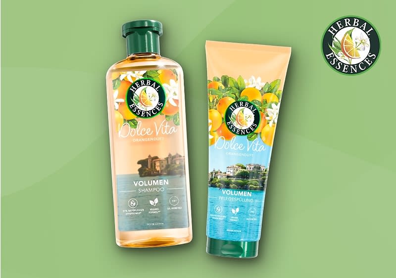Zwei Produktverpackungen von Herbal Essences Dolce Vita Volumen Shampoo und Conditioner auf einem grünen Hintergrund, die Shampoo-Flasche ist durchsichtig mit einem grünen Deckel und zeigt Bild von Orangenblüten und einer Villa, die Tube des Conditioners hat  ähnliches Design mit Orangen und Blüten, beide Verpackungen tragen Herbal Essences Logo mit rosa Blume und Aufschrift Dolce Vita sowie Volumen in weißer Schrift, oben rechts das Herbal Essences Logo mit rosa Blume auf grünen Kreis