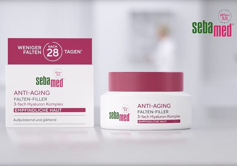 Eine Produktverpackung von Sebamed Anti-Aging Falten-Filler, bestehend aus einer weißen Schachtel mit rotem und grünem Text sowie einem weißen Tiegel mit rotem Deckel. Auf der Schachtel steht „Weniger Falten nach 28 Tagen“, „Anti-Aging Falten-Filler“, „3-fach Hyaluron Komplex“, „Empfindliche Haut“, „Aufpolsternd und glättend“. Der Tiegel trägt ähnliche Aufschriften. Links oben das Sebamed-Logo, rechts oben der Hinweis „pH-Wert 5.5“.