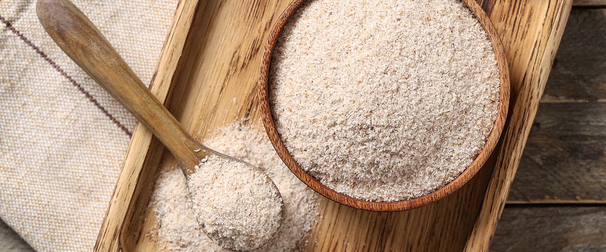 Vollkornmehl in Holzschale und Löffel auf Holzbrett