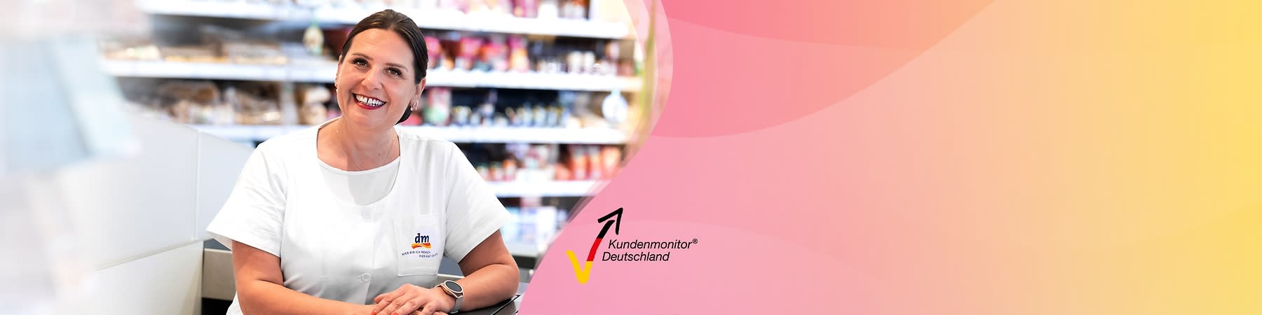 Eine Person in weißer Arbeitskleidung mit dm-Logo sitzt vor einem Regal, daneben das Logo von Kundenmonitor Deutschland