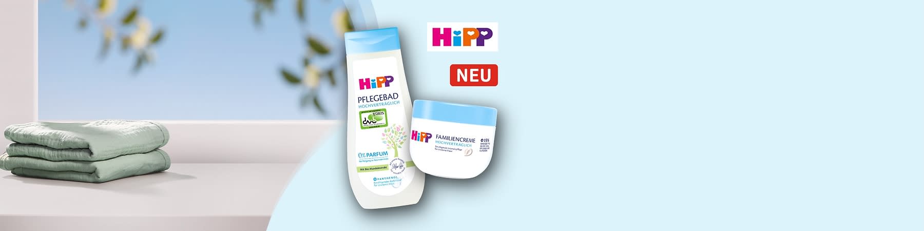 Eine weiße Flasche Pflegebad und eine weiße Dose Familiencreme der Marke HiPP, beide mit blauen Deckeln und der Aufschrift „Hochverträglich“