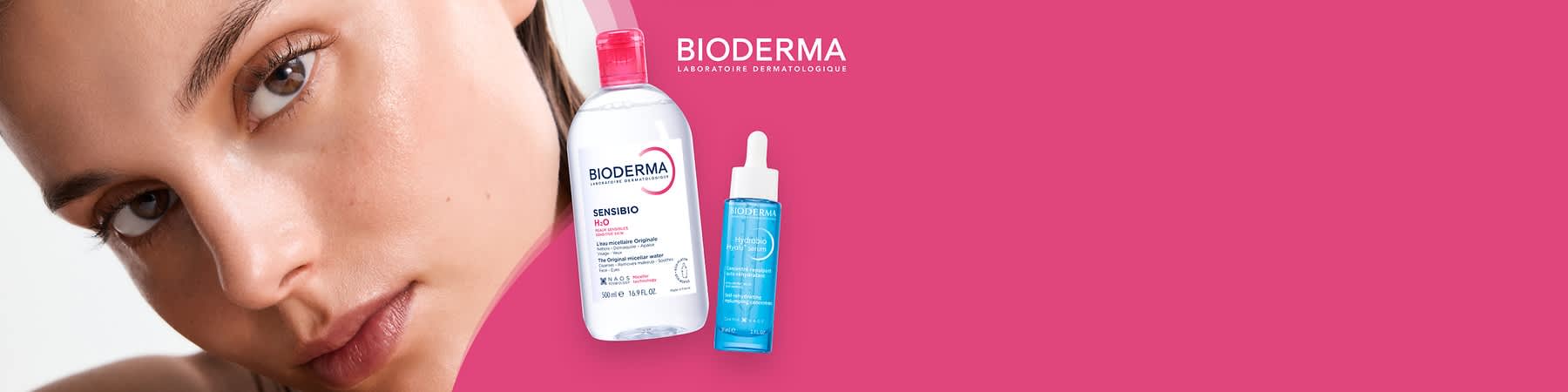 Eine transparente Flasche mit rotem Verschluss und der Aufschrift „BIODERMA Sensibio H2O“ neben einer blauen Flasche mit Pipette und der Aufschrift „BIODERMA Hydrabio Serum“ vor einem pinken Hintergrund mit dem Text „BIODERMA Laboratoire Dermatologique“ oben rechts