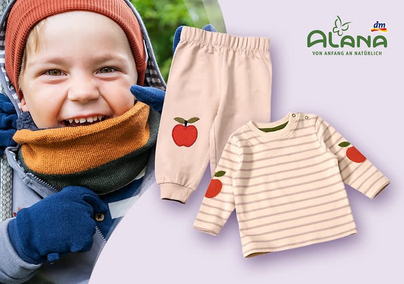 Lachendes Kleinkind mit Mütze, Schal und Handschuhen links, rechts zwei Babyklamotten in Hellrosa mit Apfel-Motiv: eine gestreifte Langarmshirt und eine Jogginghose, oben rechts grünes Logo „ANANA“ und kleiner Slogan