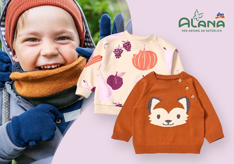 Ein beiger Kinderpullover mit bunten Herbstmotiven wie Kürbissen und Trauben, daneben drei Paar Socken in Braun, Beige und Lila mit Herbstmotiven, oben rechts das Logo von Alana