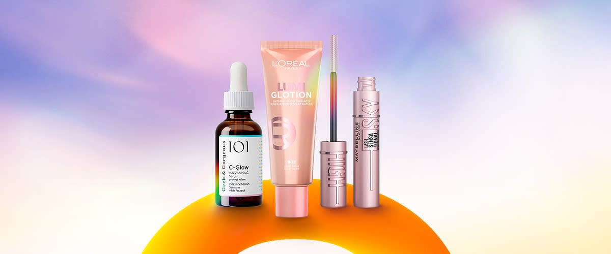 Vier Kosmetikprodukte vor einem farbigen Hintergrund: Eine braune Flasche mit weißem Tropfverschluss und der Aufschrift „101 C-Glow“, eine rosa Tube mit der Aufschrift „L'Oreal Lumi Glotion“, ein silberner Mascara-Stift mit der Aufschrift „Benefit“, und ein rosa Mascara mit der Aufschrift „Maybelline Sky High“