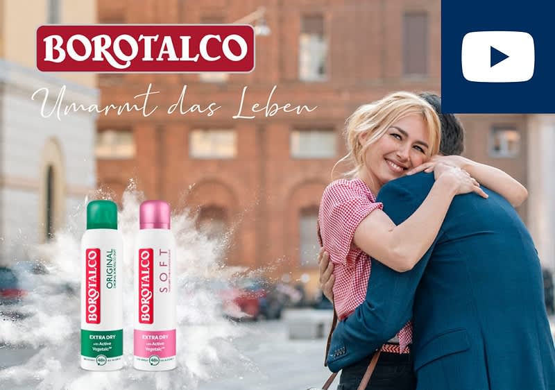 Zwei Borotalco Deosprays, eines in Grün mit der Aufschrift „Original“ und eines in Rosa mit der Aufschrift „Soft“, umgeben von einem Nebel. Darüber der Schriftzug „Umarmt das Leben“ und das Borotalco-Logo.