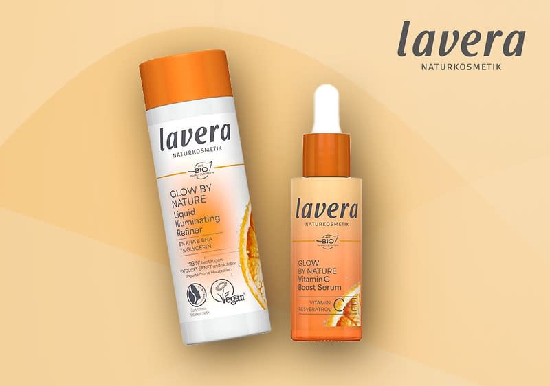 Zwei Produktverpackungen der Marke Lavera Naturkosmetik, links eine orangefarbene Flasche mit der Aufschrift „Glow by Nature Liquid Illuminating Refiner“, rechts ein orangefarbenes Fläschchen mit der Aufschrift „Glow by Nature Vitamin C Boost Serum“