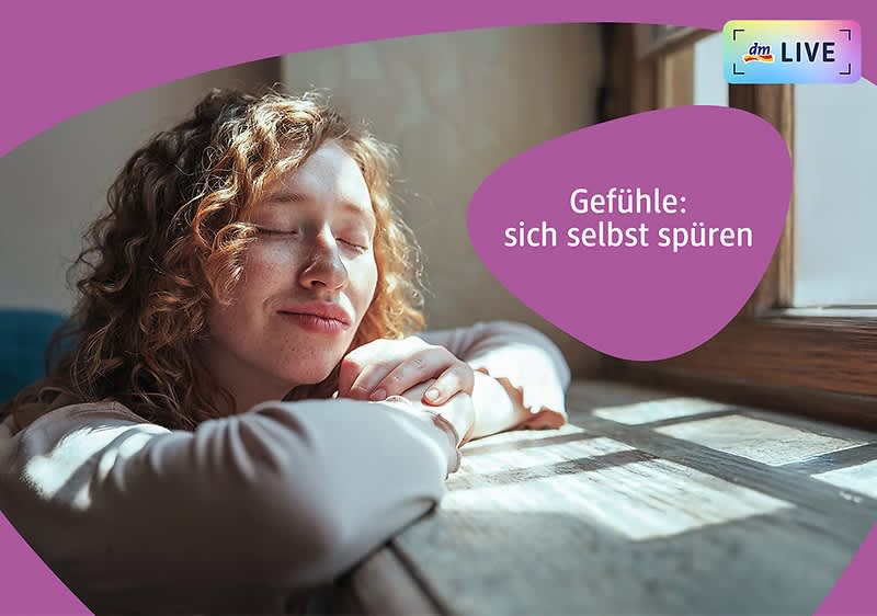 Eine Person mit lockigem Haar lehnt sich mit verschränkten Armen auf eine Fensterbank, während Sonnenlicht durch das Fenster fällt. Der Text „Gefühle: sich selbst spüren“ ist in einem lila Feld rechts neben der Person zu sehen. Oben rechts befindet sich das dm LIVE Logo.
