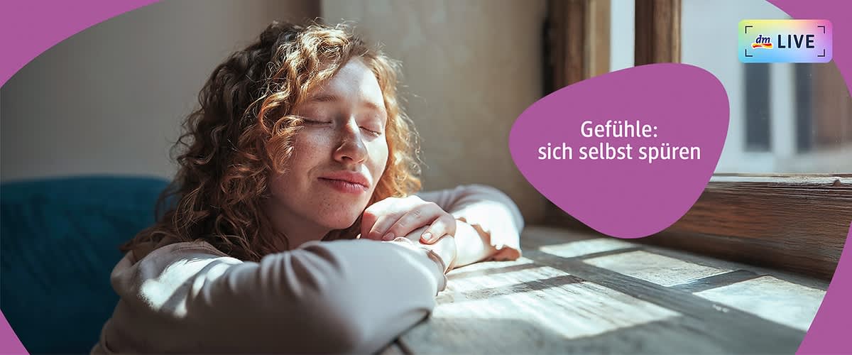 Eine Person mit lockigem Haar lehnt sich mit verschränkten Armen auf eine Fensterbank, während Sonnenlicht durch das Fenster fällt. Der Text „Gefühle: sich selbst spüren“ ist in einem lila Feld rechts neben der Person zu sehen. Oben rechts befindet sich das dm LIVE Logo.