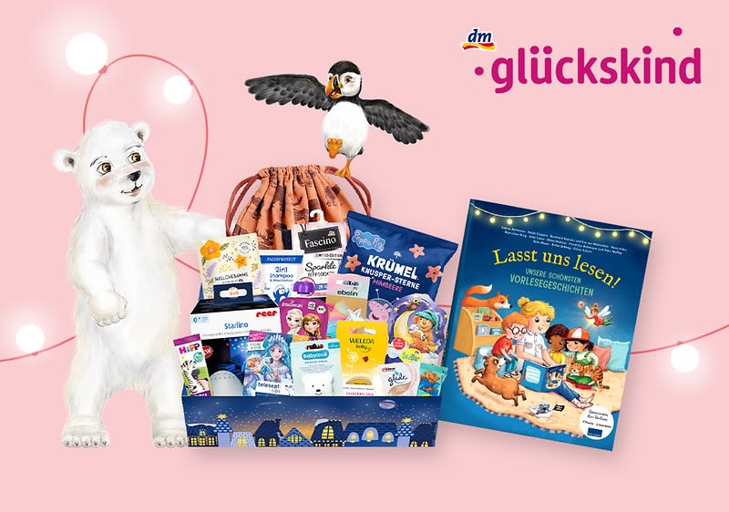 Ein weißer Eisbär steht neben einem Geschenkkorb, aus dem ein Pinguin herausragt. Der Korb enthält verschiedene Kinderprodukte, darunter Bücher und Pflegeartikel. Rechts ist ein Kinderbuch mit dem Titel „Lasst uns lesen! Unsere schönsten Vorlesegeschichten“ zu sehen. Oben rechts steht „dm glückskind“ in pinker Schrift.