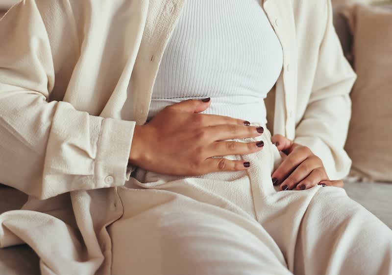 Frau hält sich den Bauch wegen Blähungen