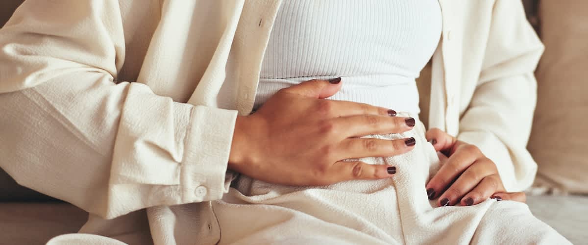 Frau hält sich den Bauch wegen Blähungen