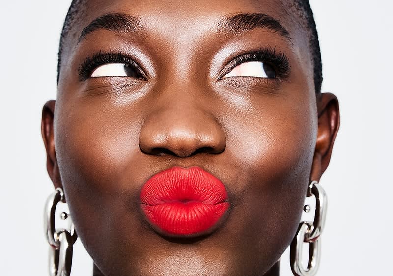 Eine Person macht einen Kussmund und trägt roten Lippenstift