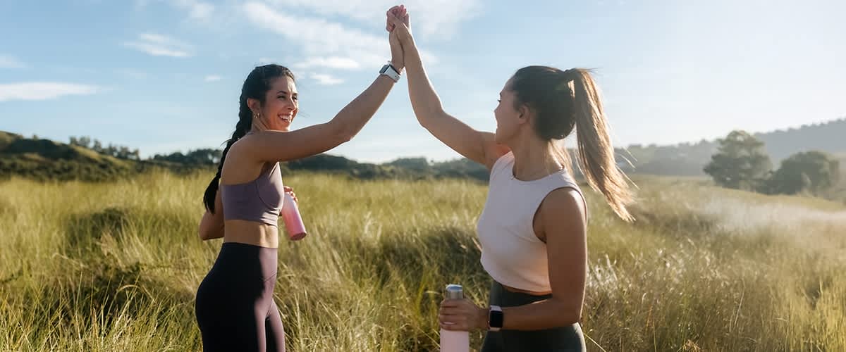 Zwei Frauen geben sich ein High Five in Sportkleidung