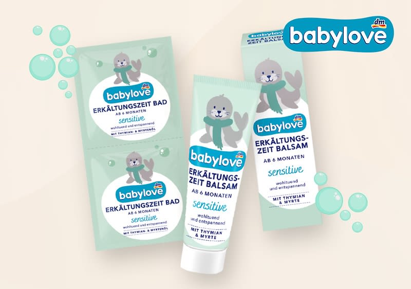 Produktverpackungen der Marke babylove mit einem niedlichen Robben-Design, bestehend aus zwei grünen Sachets mit der Aufschrift „Erkältungszeit Bad ab 6 Monaten sensitive“ und einer grünen Tube mit der Aufschrift „Erkältungszeit Balsam ab 6 Monaten sensitive“