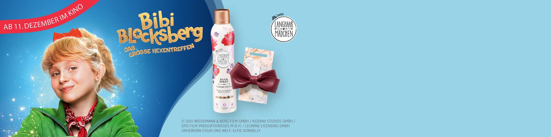 Eine Produktverpackung des Langhaar Mädchen Zauber Sprays mit Blumenmuster und der Aufschrift „Zauber Spray“ neben einer roten Haarspange in Schleifenform auf einer Verpackung mit Blumenmuster, oben links ein roter Banner mit der Aufschrift „Ab 11. Dezember im Kino“ und das Langhaar Mädchen Logo