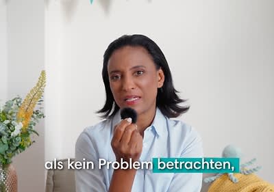 Dr. Karella Easwaran hält ein Mikrophon in der Hand, daneben der Text „als kein Problem betrachten“ in weißer und türkisfarbener Schrift.