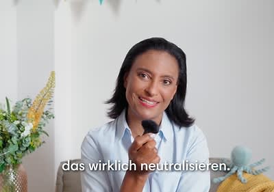 Dr. Karella Easwaran hält ein Mikrophon in der Hand, darunter der Text „das wirklich neutralisieren“