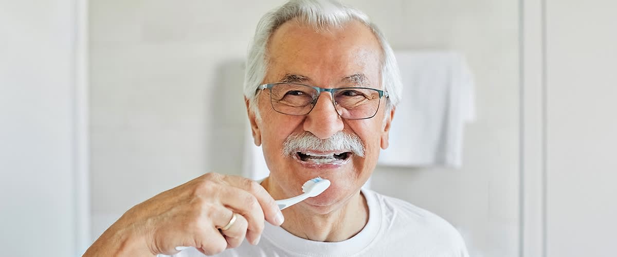 Mann mit weißen Haaren und weißem Bart putzt sich die Zähne