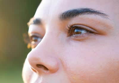 Man sieht die braunen Augen einer Frau in Nahaufnahme.