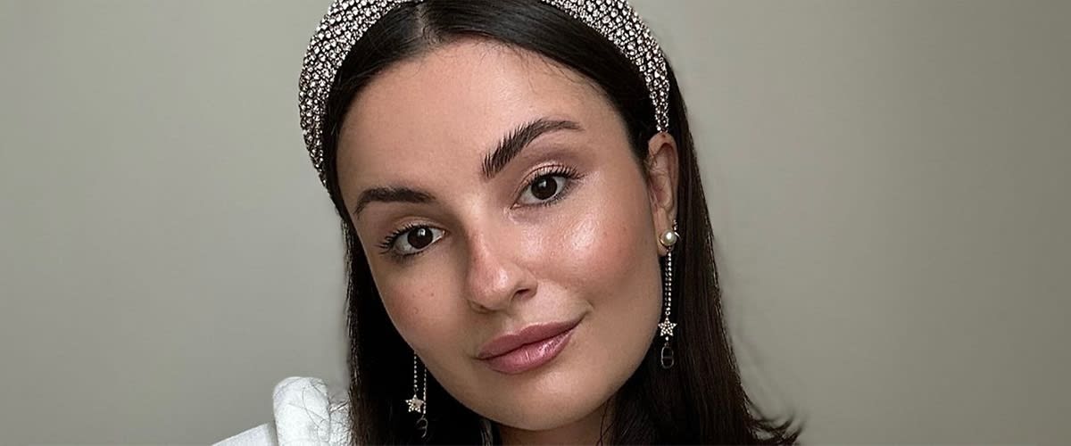 Eine Frau trägt ein mit Perlen besetztes Haarband und lange Ohrringe mit Sternanhänger. Ihr Make-up ist dezent gehalten. Sie trägt einen leichten rosefarbenen Lipgloss und goldigen Lidschatten.