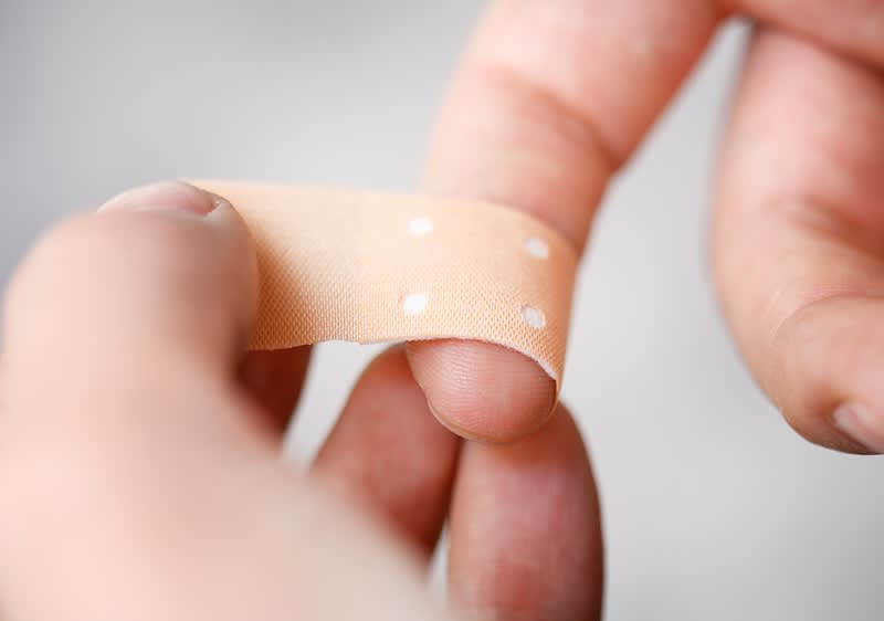 Auf einen Finger wird eine Schnittwunde mit einem Pflaster überklebt.