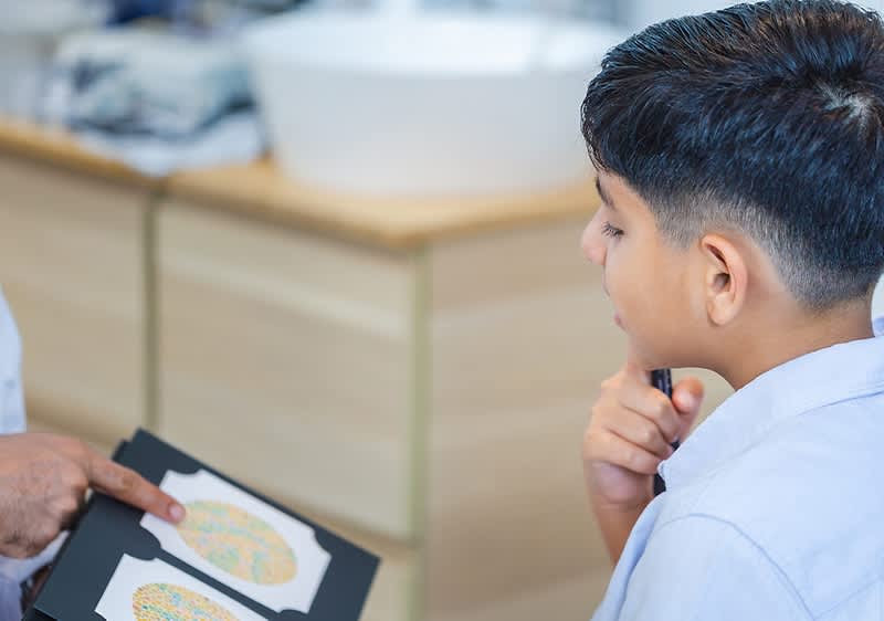 Ein Mann hält ein Buch mit einer bunten Illustration eines Gehirns in der Hand, während er mit einem Jungen spricht, dessen Gesicht unscharf ist