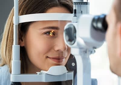 Man sieht eine junge Frau beim Augenarzt bei der Vermessung ihrer Netzhaut