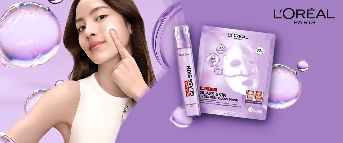 Lila Verpackung einer L'Oréal Paris Revitalift Glass Skin Hydrogel Glow Mask mit der Aufschrift „90% Inhaltsstoffe natürlichen Ursprungs“ und einem lila Flakon mit der Aufschrift „Revitalift Glass Skin“