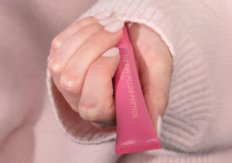 Eine Hand hält eine rosa Tube mit der Aufschrift „THE PINK PILLOW PEPTIDE“