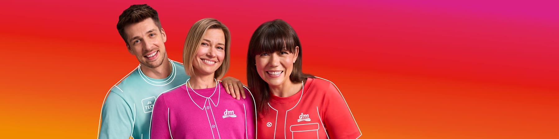 Drei Personen tragen bunte dm-Uniformen vor einem orange-pinken Hintergrund. Die linke Person trägt ein türkisfarbenes Shirt mit der Aufschrift „Tech“, die mittlere Person ein pinkes Shirt mit dm-Logo, und die rechte Person ein rotes Shirt mit einem weißen Symbol.