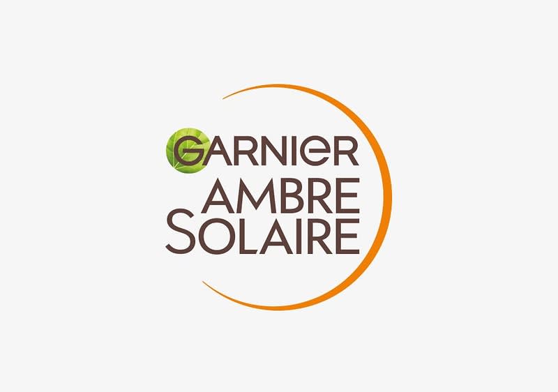 Das Logo von Garnier Ambre Solaire mit einem grünen Blattmotiv und einem orangefarbenen Halbkreis.