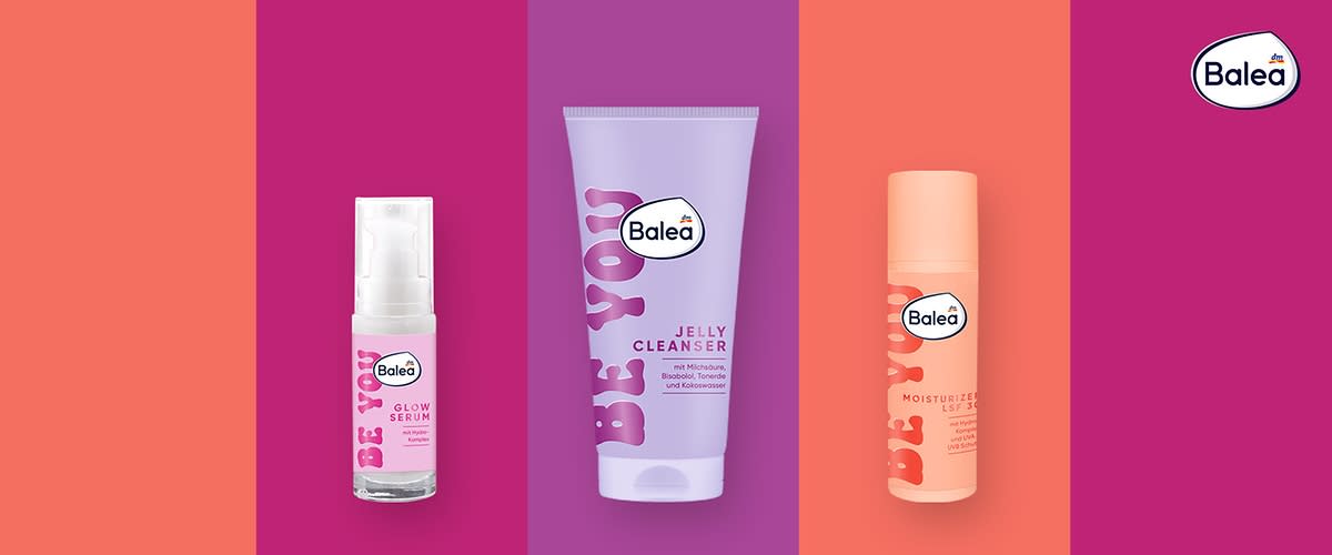 Drei Balea-Produkte vor einem pastellfarbenen Hintergrund: Links ein Glow Serum in einer transparenten Flasche, in der Mitte ein orangefarbener Moisturizer, rechts ein lila Jelly Cleanser. Alle Produkte tragen den Schriftzug „BE YOU“ und das Balea-Logo.