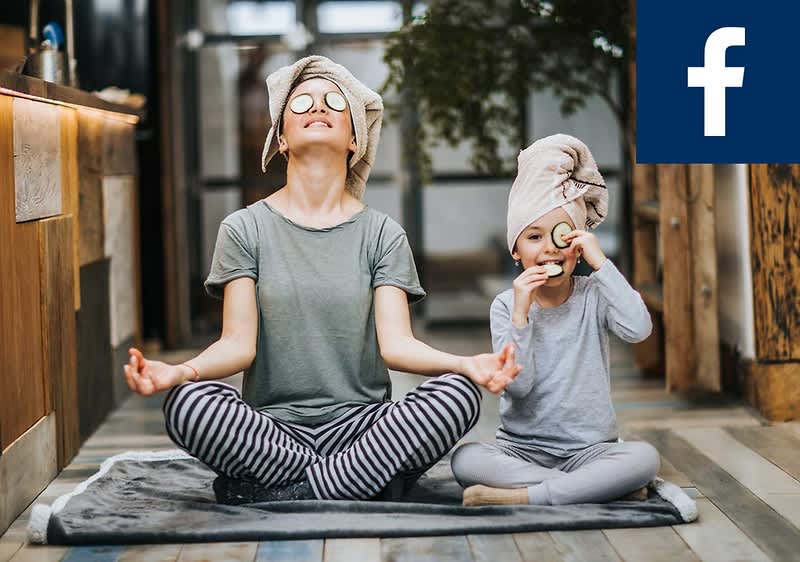 Eine Person im Schneidersitz und ein Kind sitzen auf einem Teppich und machen Yoga. Beide haben Handtücher um den Kopf gewickelt. Oben rechts ist das Facebook-Logo.
