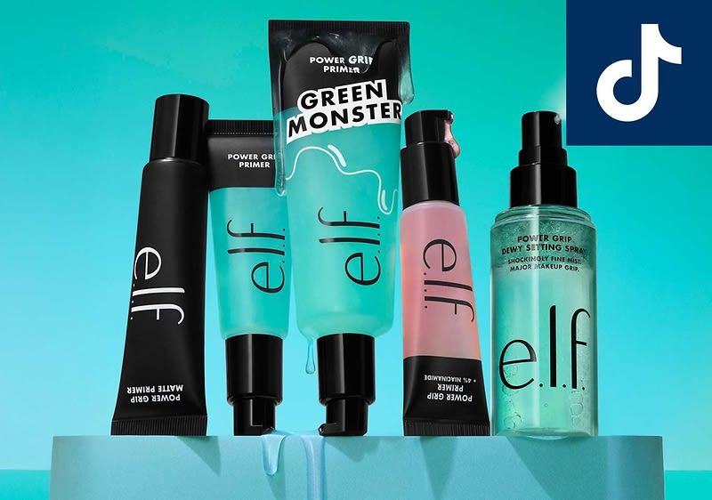 Eine Sammlung von elf Kosmetikprodukten, darunter Tuben und Flaschen mit der Aufschrift „Power Grip Primer“ und „Green Monster“, vor einem türkisfarbenen Hintergrund. Oben rechts das TikTok-Logo