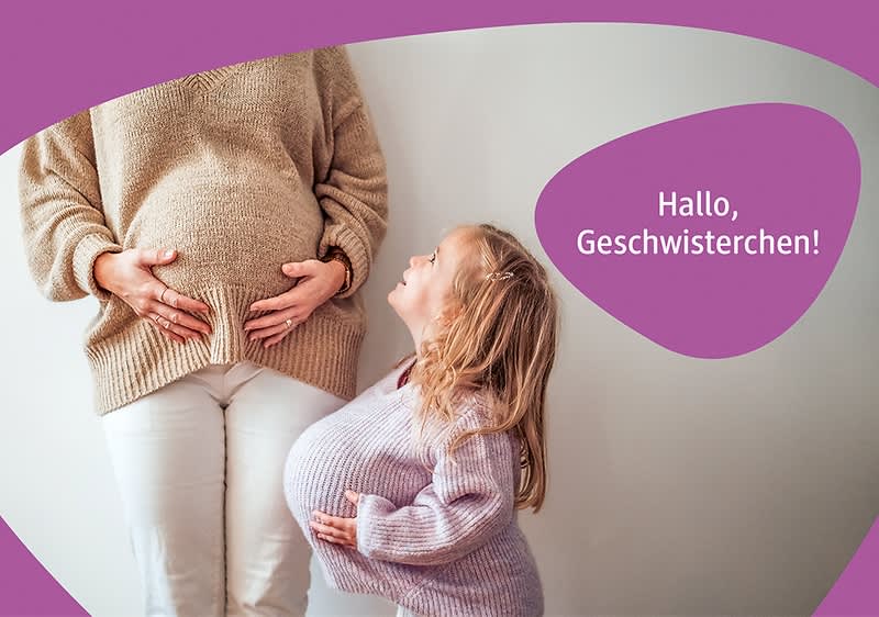Eine schwangere Frau in einem beigen Pullover steht neben einem kleinen Mädchen, das einen lila Pullover trägt und einen künstlichen Babybauch hat.