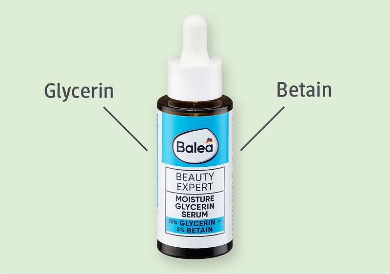 Braunes Tropfflaschen-Serum der Marke Balea mit blauer Etikette, Aufschrift „Beauty Expert Moisture Glycerin Serum 15% Glycerin 5% Betain“, links Pfeil und Text „Glycerin“, rechts Pfeil und Text „Betain“