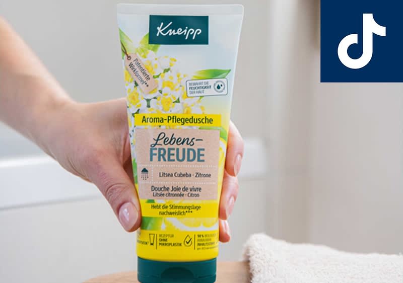 Eine Hand hält eine Tube Kneipp Aroma-Pflegedusche mit der Aufschrift „Lebensfreude Litsea Cubeba - Zitrone“. Oben rechts ist das TikTok-Logo zu sehen.
