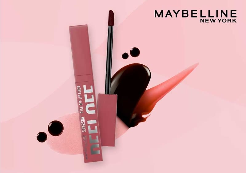 rosa-violette Maybelline Superstay Peel Off Lip-Gloss-Verpackung mit aufgesetztem Applikator und Lippenfarbspuren vor rosa Hintergrund, oben rechts Schriftzug „MAYBELLINE NEW YORK“