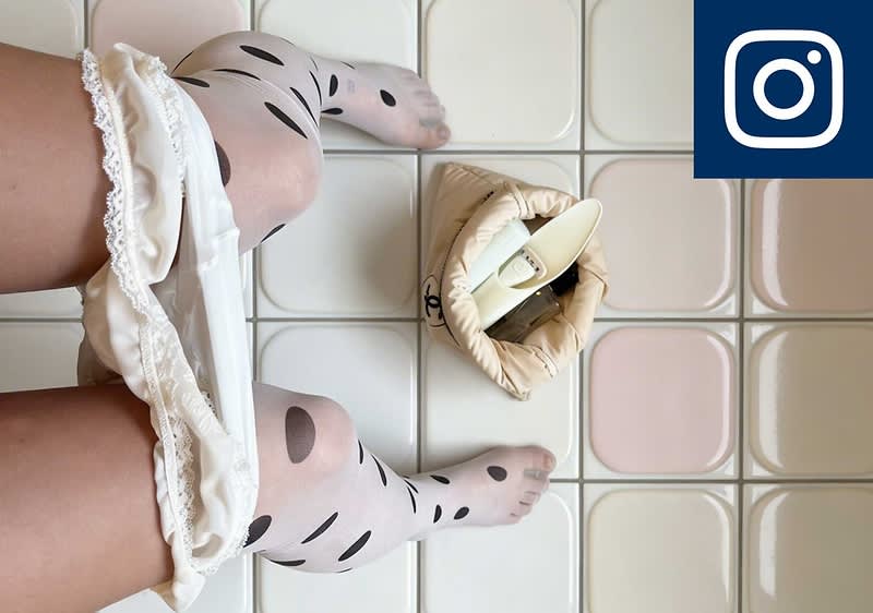Person mit weißen Strümpfen mit schwarzen Punkten sitzt auf einem gefliesten Boden. Die Perspektive ist von oben, die Person sitzt wahrscheinlich auf einer Toilette. Neben ihr eine beige Tasche mit einem beigem Rasierer. Oben rechts das Instagram-Logo.