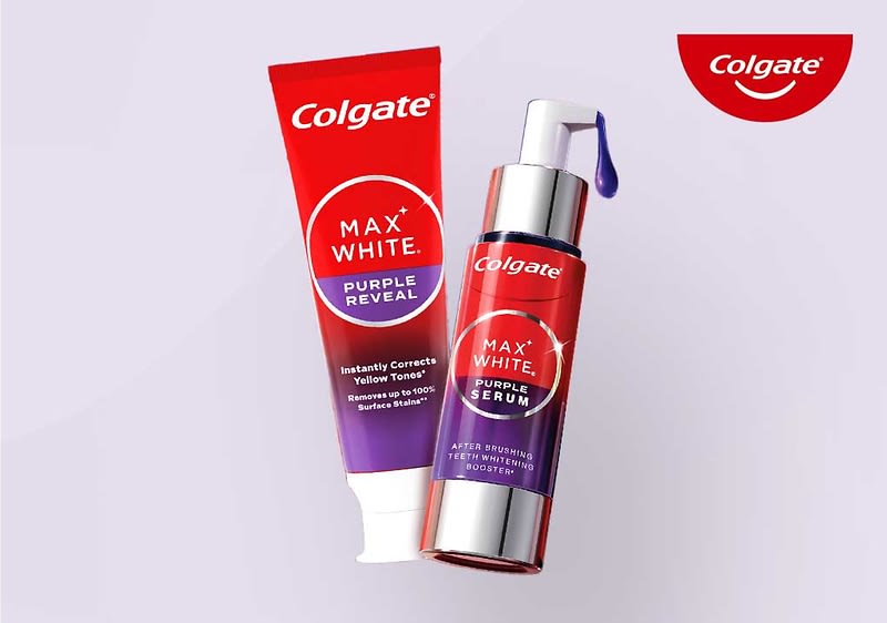 Eine rote Zahnpastatube und ein rotes Serumfläschchen der Marke Colgate mit der Aufschrift „Max White Purple Reveal“ und „Purple Serum“. Oben rechts das Logo von Colgate