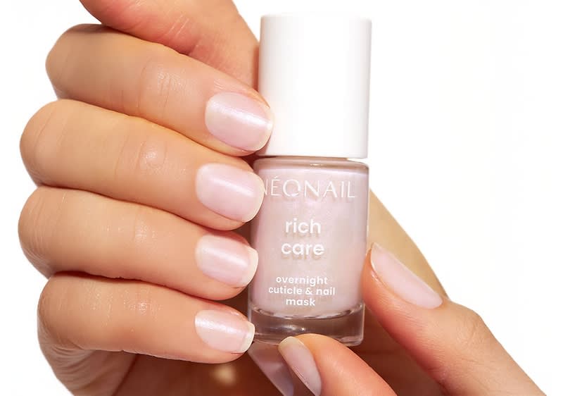 Eine Hand hält eine Flasche mit der Aufschrift „NEONAIL rich care overnight cuticle & nail mask“. Die Nägel sind gepflegt und glänzend rosa lackiert.
